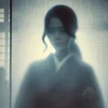 A symbolic representation of the mystery surrounding the beautiful mother of actress Suzu Hirose. The image features a blurred, shadowed figure of a Japanese woman behind a translucent screen, emphasizing secrecy and non-disclosure. The atmosphere is enigmatic, with soft lighting creating an air of intrigue. The background is minimal, drawing focus to the hidden identity of the woman.